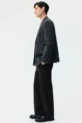 Pantalón de corte relajado color negro, con cintura elástica, cierre frontal con botón y cordón de ajuste oculto. Presenta piernas con raya marcada, bolsillos laterales al bies y bolsillos traseros ribeteados con botón.
