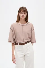Remera de algodón color crudo, con cuello redondo a la base, mangas 3/4 holgadas y costuras con pespuntes en tono contrastante.