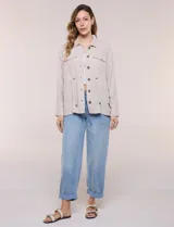 Sobrecamisa beige de lino liviano, con cuello camisero, cierre frontal de botones carey y bolsillos en el pecho. Cuenta con cordón ajustable en la cintura y mangas largas.