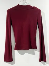 Remera de manga larga color negro, con escote en V y mangas acampanadas tipo Oxford. Confeccionada en tejido de algodón elastizado, con un diseño entallado al cuerpo.