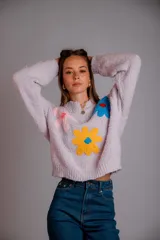 Buzo de punto color fucsia, con cuello redondo, manga larga y bordado de flores en amarillo y azul en el frente.