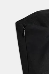 Top negro strapless con escote recto y bajo acabado en peplum. Cuenta con cierre lateral con cremallera oculta en costura.