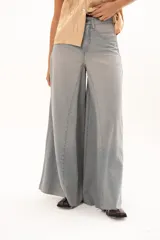 Pantalón de jean tiro alto con diseño de pierna extra ancha y caída fluida. Presenta costuras verticales que realzan su estructura, bolsillos funcionales y terminación de ruedo deshilachado.