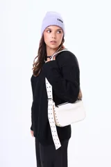 Bandolera de color blanco con cierre superior y correa ancha ajustable con ojales metálicos decorativos.