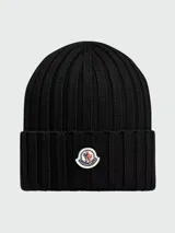 Gorro tipo beanie de lana acanalada en color negro, con parche del logo de la marca en la parte frontal.