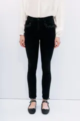 Jean slim negro de tiro medio-alto, con calce al cuerpo y pierna semi-recta. Presenta detalles de hotfix en los bolsillos delanteros y en los puños.
