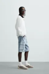 Bermuda de denim de algodón, color celeste lavado, de corte relajado (relaxed fit). Presenta cinco bolsillos, incluyendo bolsillos cargo plastrón con solapa en las perneras.