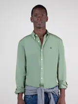 Camisa lisa verde claro de hombre, de corte regular fit, con cuello button-down, cierre frontal de botones, mangas largas con puños simples y logo bordado en el pecho.