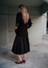 Falda midi plisada de cuero sintético en color marrón oscuro, con diseño de talle alto y caída acampanada.