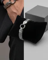 Pulsera de acero con diseño de cadena trenzada y cierre circular con detalles grabados.