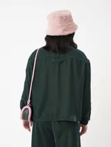 Camisa corta negra de terciopelo, de silueta cuadrada oversized, con bolsillo delantero y detalle en los puños y cuello con botón oro en forma de flor.