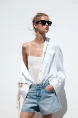 Shorts de jean color negro, tiro medio, corte mom fit, con cinco bolsillos, cierre frontal con cremallera y botón.