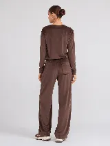 Pantalón de corte recto confeccionado en tejido plush con acabado aterciopelado. Presenta cintura elástica, bolsillos laterales y un bolsillo trasero, ofreciendo una caída fluida y cómoda.