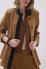 Chaqueta de lino marrón con cuello mao en contraste negro, cierre frontal con botones y hombreras.