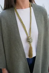 Collar largo de estilo artesanal con cordones de hilo color verde oliva, que presenta un dije central esférico compuesto por hilos metálicos entrelazados y una borla colgante del mismo tono.
