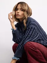 Sweater de punto con diseño de trenzas verticales, cuello alto y corte holgado. Presenta mangas largas con puños acanalados y un largo a la cadera.