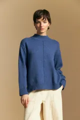 Polera de tejido de punto color blanco, con cuello alto acanalado, hombros caídos y detalle de costura vertical en el frente.