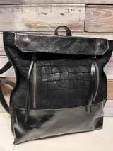 Mochila de diseño urbano en color negro, confeccionada en una combinación de cuero liso y cuero con textura tipo reptil. Presenta una solapa superior, dos cierres frontales verticales con tiradores largos y correas ajustables.