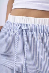 Pantalon de corte amplio y tiro bajo, confeccionado en tela de franela con estampado de cuadros en tonos blanco, negro y gris. Cuenta con cintura elástica con cordón ajustable y bolsillos laterales.