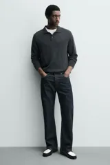 Mocasín de cuero liso, estilo penny loafer, con contraste de color blanco y negro. Presenta un antifaz superior con una abertura central y costuras visibles en el borde. Tiene suela negra de bajo tacón.