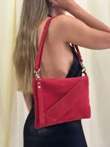 Sobre/cartera de cuero gamuza color rojo, con diseño de solapa diagonal. Incluye una correa larga y una correa corta desmontables para usar como bandolera, al hombro o en la muñeca.