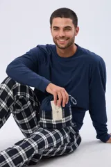 Pijama de hombre compuesto por una remera de manga larga azul marino y un pantalón a cuadros en tonos azul marino, blanco y negro.