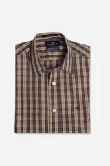 Camisa de manga corta Brooksfield con corte slim fit, confeccionada en tejido de algodón con spandex. Presenta un diseño a cuadros en tonos beige y azul marino, cierre frontal con botones y logo de la marca bordado en el pecho.