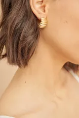 Aros tipo caravana de medio aro color dorado con textura acanalada.