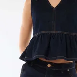 Top de denim color azul oscuro, sin mangas, con escote en V y detalle de volados en la parte inferior. Costuras en contraste de hilo ocre.
