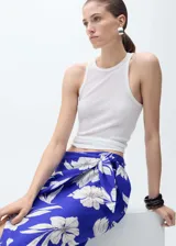 Falda midi tipo pareo con diseño recto, tiro medio y cintura elástica. Presenta un estampado floral en tonos azul y blanco, con un detalle de nudo lateral.