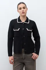 Chaqueta tejida de punto color naranja, con cuello camisero, cierre frontal de botones y dos bolsillos frontales con solapa. Presenta detalles de bordado en contraste en el cuello y los bolsillos.