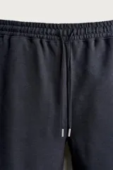 Bermuda estilo jogger de ajuste relajado, confeccionada en tejido interlock de algodón. Cuenta con cintura elástica ajustable con cordón, bolsillos frontales de vivo y diseño liso.
