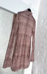 Minivestido de microtul elastizado con estampado animal print en tonos marrones. Diseño ajustado al cuerpo, cuello alto y mangas largas acampanadas.