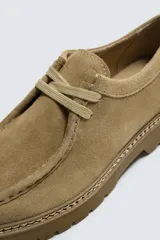 Zapato de cordones para hombre confeccionado en piel con acabado de serraje en color beige. Cuenta con detalle de bordón en el empeine, horma redonda y suela tipo track a tono.