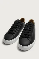 Zapatilla de estilo minimalista con cordones, confeccionada en material sintético de acabado mate. Presenta una horma redonda, forro interior en tono contrastante y suela de goma con textura ligera.