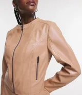 Campera básica de cuero sintético (PU) color marrón oscuro, con cuello redondo, cierre frontal y recortes decorativos. Cuenta con mangas largas y bolsillos con cierre.