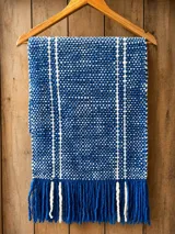 Pashmina de lana merino tejida a mano, color azul con rayas verticales blancas y flecos en los extremos.