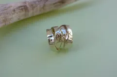 Anillo de diseño enlazado con textura irregular, realizado a mano en bronce. Presenta un diseño abierto que permite regular su tamaño con suavidad.