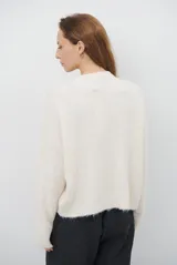 Buzo de tejido de punto en color beige, con cuello redondo y mangas largas. Presenta un delicado bordado de ramas y hojas en color crema en la parte superior del frente.