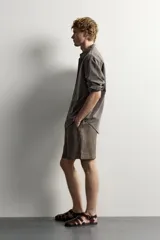 Bermuda de lino negro de corte relaxed fit, con cintura elástica ajustable mediante cordón y bolsillos frontales.