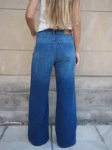 Pantalón jean de tiro medio, corte recto y amplio con caída estilo wide leg, en tono azul clásico.