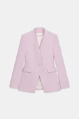 Blazer entallado color lila sin solapa, con escote en V, manga larga y bolsillos con solapa en los laterales. Presenta detalle de encaje combinado a tono en el escote y cierre frontal con un botón forrado.