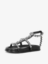 Sandalias planas color blanco con tiras decoradas con tachas plateadas y cierre de velcro.