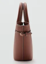 Cartera de mano color marrón, de diseño estructurado tipo trapecio, con doble asa corta y detalles de correas laterales ajustables con hebilla.