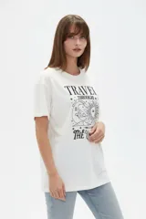 Remera de algodón manga corta, corte holgado, con cuello redondo y estampado frontal en negro con la frase "Travel through the universe" y motivos celestes de sol, luna y estrellas.