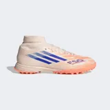 Championes de fútbol Adidas F50 Sparkfusion League, diseñados para mujer. El calzado es de caña media con cuello tejido, exterior en tono beige claro con franjas azules y detalles en naranja coral en la suela.