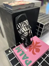 Sandalias chatas con tiras de cuero con estampado de cebra y base cuadrada.