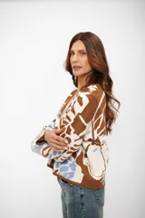 Saco de punto con escote en V y cierre frontal de botones. Presenta un diseño estampado con formas abstractas en tonos marrón, blanco y celeste.