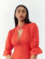 Vestido color naranja con escote en V, mangas 3/4 con volados y botones decorativos en el frente.