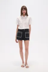 Short de jean color azul oscuro, de calce alto y ajustado al cuerpo. Presenta dos bolsillos frontales cuadrados con bordado decorativo en color blanco.